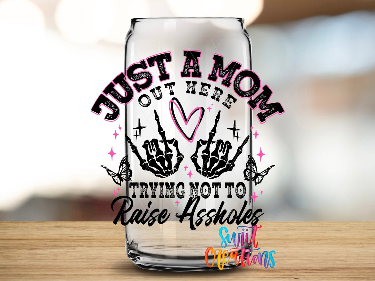 Just a Mom Trying Not To Raise Assholes UV DTF transfer applied to a clear glass can from Swiit Creations